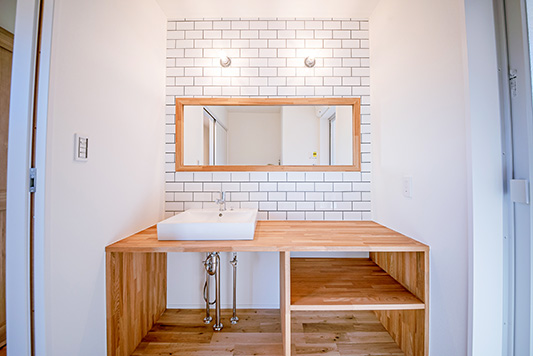 造作の洗面台のある、ホワイトタイルの壁が爽やかな洗面室。